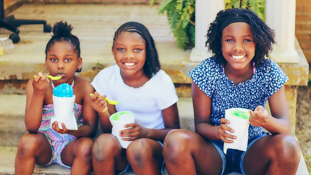 Three young black girls celebrate with ice cream at Dermott, Arkansas' Entrepreneurship Extravaganza.