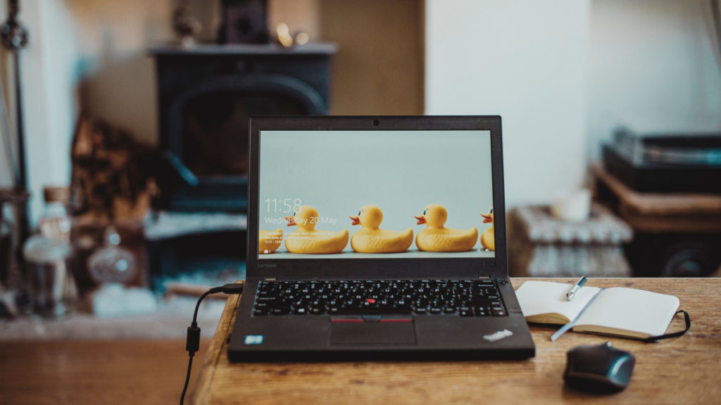 A laptop and a journal are set up on a kitchen table, looking out over a living room with a cast iron wood stove.