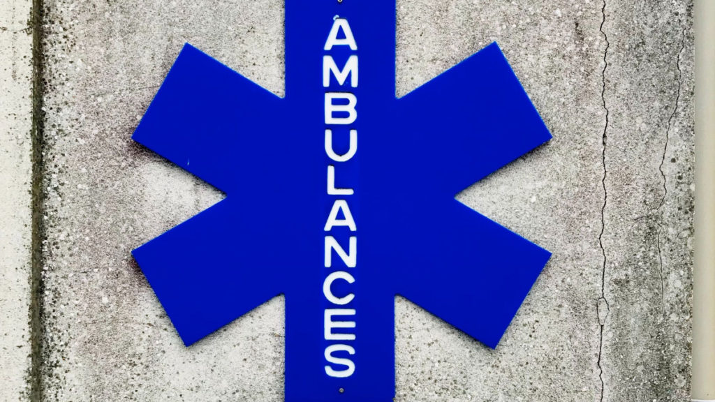 A blue 6-pointed asterisk sign with the word AMBULANCES on it.